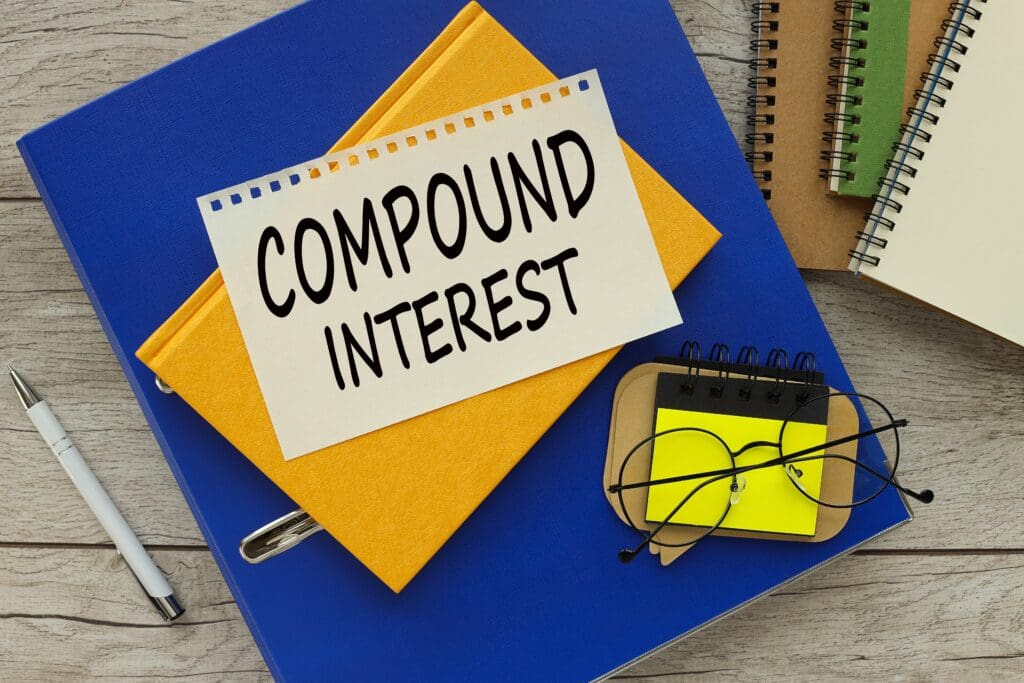 A notebook with 'Compound Interest' written on a label and glasses on top.