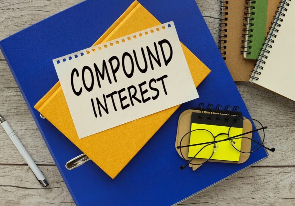 A notebook with 'Compound Interest' written on a label and glasses on top.